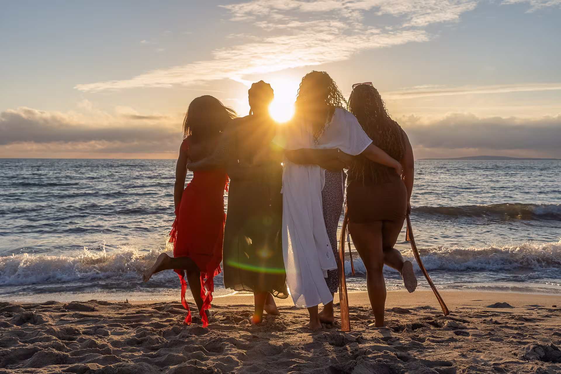 Freunde beim Sonnenuntergang am Strand von Santa Ponça auf Mallorca, Arm in Arm mit Blick aufs Meer, warmes Licht und emotionale Urlaubsstimmung