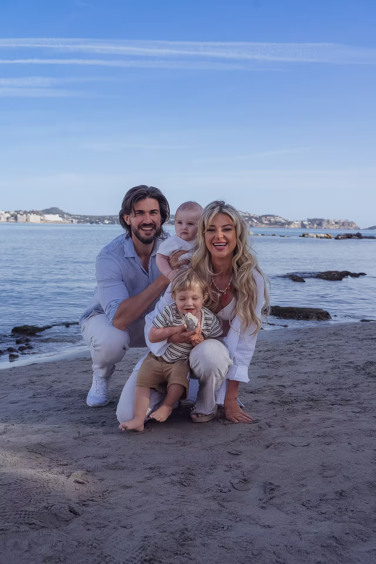 Junge Familie mit 2 Kindern sitzt zusammen am Meer